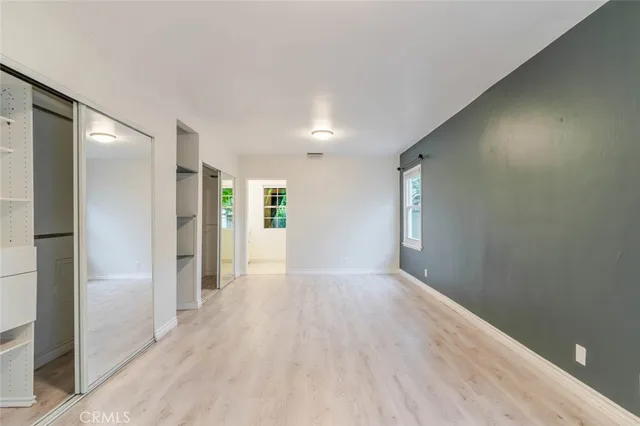 a view of an empty room with kitchen and window