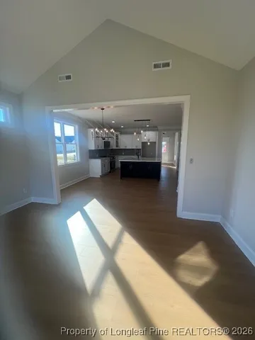 a view of an empty room with window and wooden floor