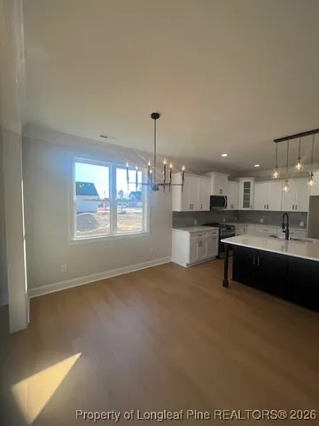 a large white kitchen with kitchen island a sink stainless steel appliances and cabinets