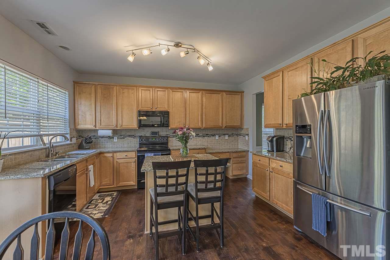 7759 San Gabriel Street Raleigh, NC 27613 - Photo 13 of 30 a kitchen with stainless steel appliances granite countertop a refrigerator a stove a sink dishwasher a dining table and chairs with wooden floor