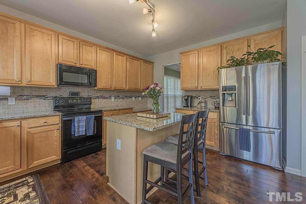 7759 San Gabriel Street Raleigh, NC 27613 - Photo 15 of 30 a kitchen with kitchen island granite countertop wooden cabinets and stainless steel appliances