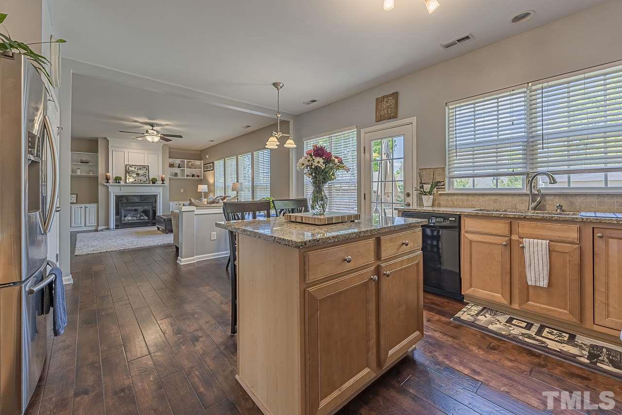 7759 San Gabriel Street Raleigh, NC 27613 - Photo 16 of 30 a kitchen with kitchen island granite countertop a stove a sink a refrigerator and wooden cabinets