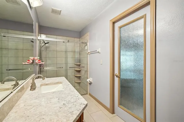 a bathroom with a granite countertop sink a mirror and a shower