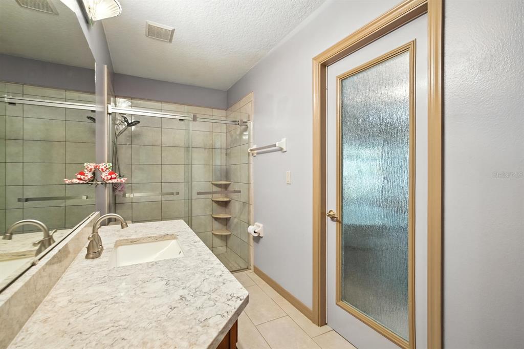 29933 Fullerville Road DeLand, FL 32720 - Photo 23 of 57 a bathroom with a granite countertop sink a mirror and a shower
