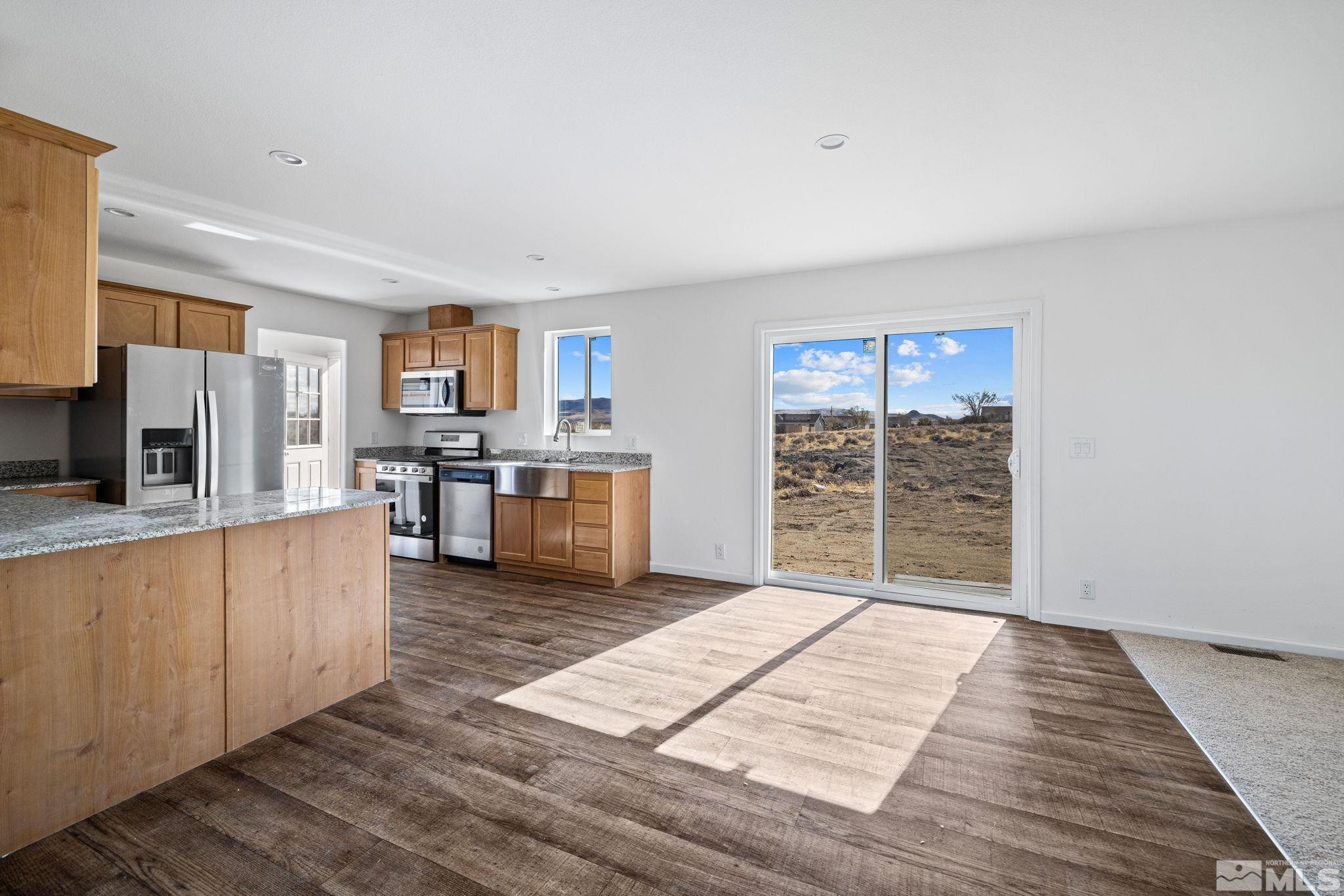 1435 East 8th Street Silver Springs, NV 89429 - Photo 16 of 30 a open kitchen with stainless steel appliances granite countertop a stove top oven a sink dishwasher and a refrigerator with wooden floor