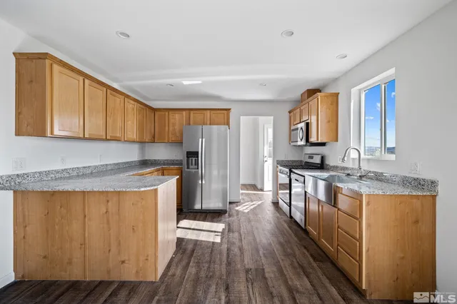 a kitchen with stainless steel appliances granite countertop a stove a sink dishwasher a refrigerator and cabinets with wooden floor