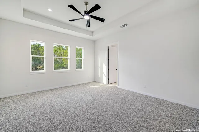 an empty room with windows and ceiling fan
