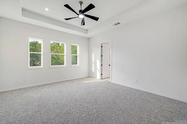 an empty room with windows and ceiling fan