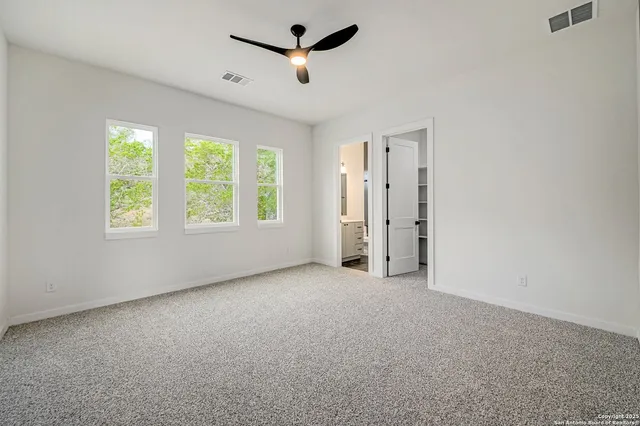 an empty room with windows and ceiling fan