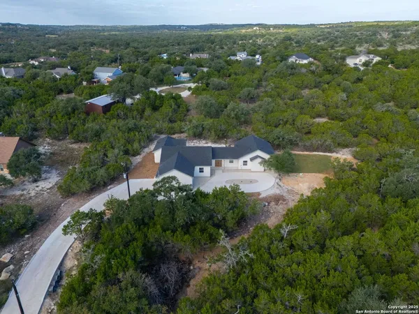 an aerial view of residential houses with outdoor space and trees