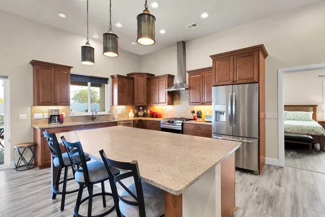 a kitchen with stainless steel appliances a dining table chairs refrigerator and microwave