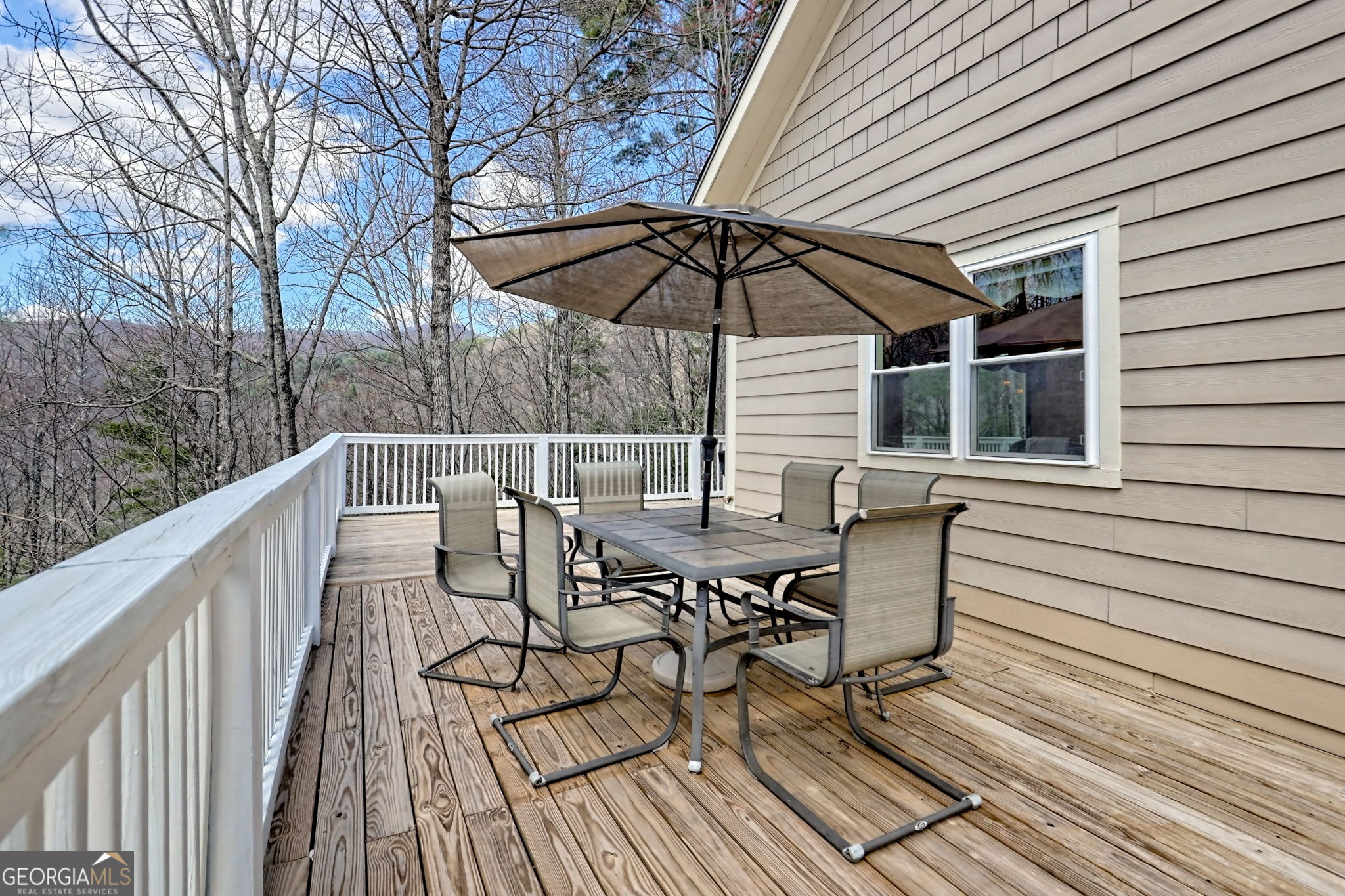1068 Coleman River Road Clayton, GA 30525 - Photo 27 of 86 a view of deck with table and chairs under an umbrella with wooden floor and fence