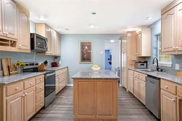 a kitchen with stainless steel appliances granite countertop a stove a sink dishwasher and a refrigerator with wooden cabinets