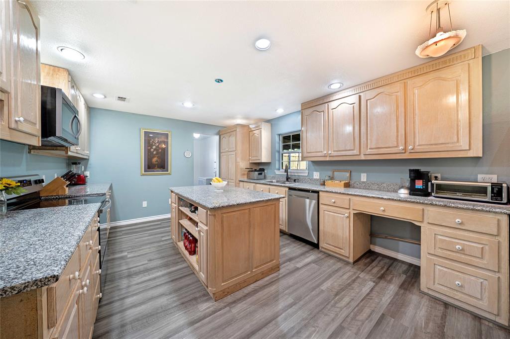 1511 North Walnut Grove Road Midlothian, TX 76065 - Photo 13 of 39 a kitchen with granite countertop kitchen island wooden floors and stainless steel appliances