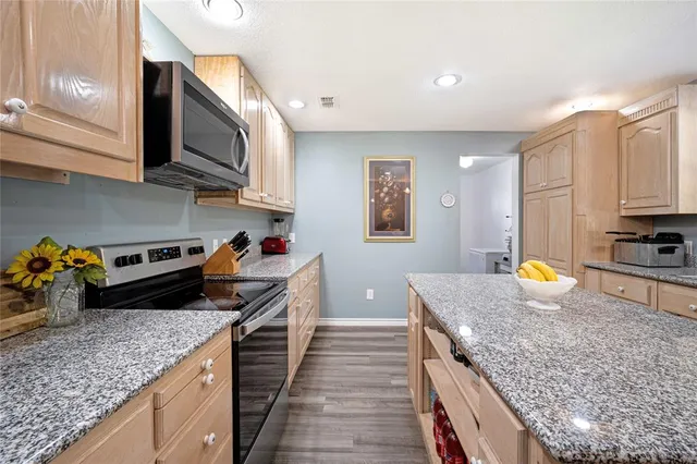 a kitchen with stainless steel appliances granite countertop a stove a sink and a microwave
