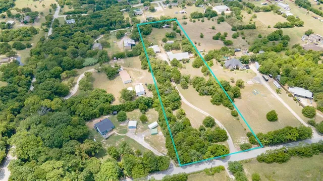 an aerial view of residential houses with outdoor space and trees