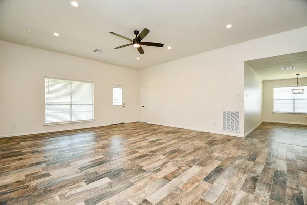 an empty room with wooden floor and windows