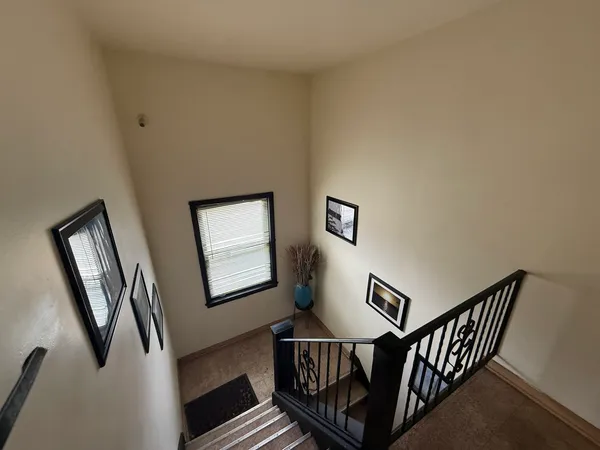 a view of staircase with lots of frames on wall and a window