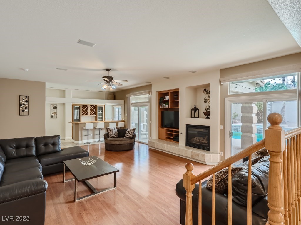 1221 Fragrant Spruce Avenue Las Vegas, NV 89123 - Photo 18 of 59 Living area featuring built in shelves, healthy amount of natural light, wood finished floors, bar area, and ceiling fan with light