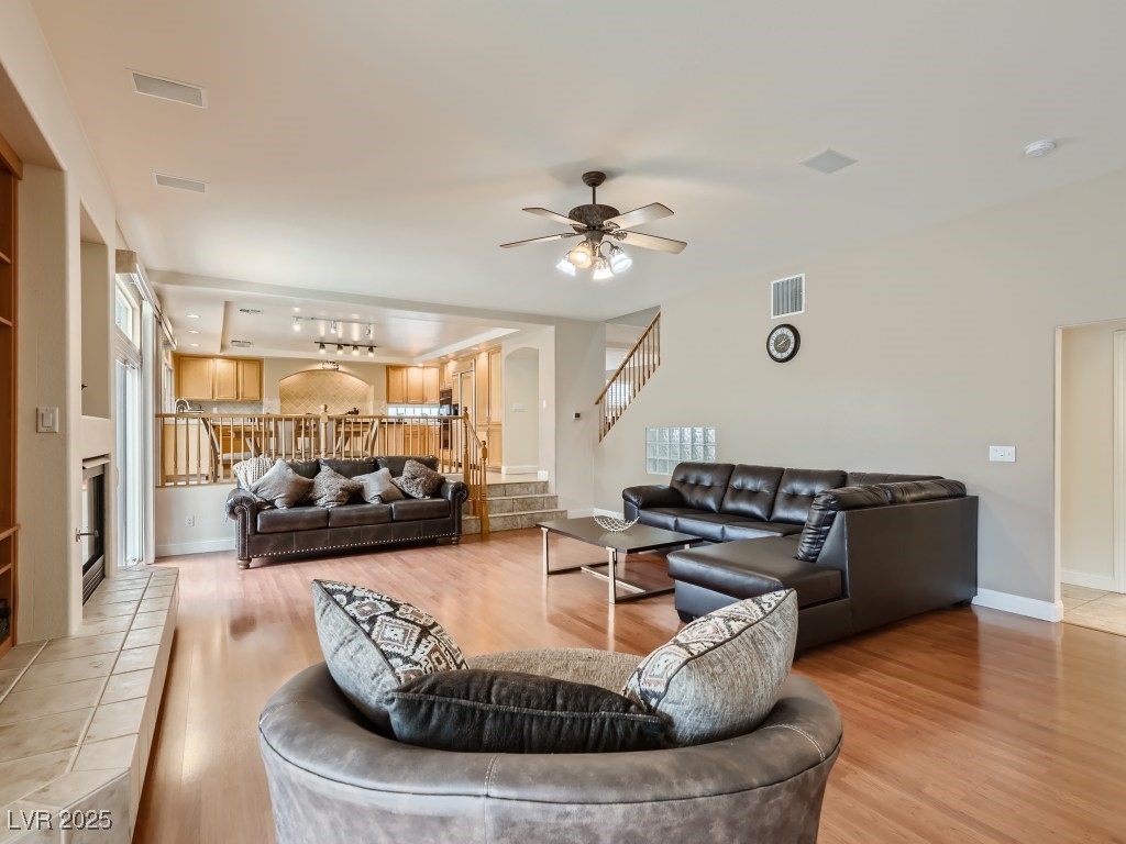 1221 Fragrant Spruce Avenue Las Vegas, NV 89123 - Photo 21 of 59 Living room with light wood-type flooring, stairs, ceiling fan with light, a chandelier, and a tile fireplace