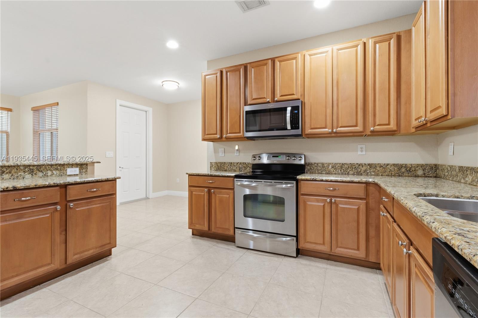 27049 Southwest 142nd Avenue Homestead, FL 33032 - Photo 19 of 36 a kitchen with granite countertop a stove top oven microwave and cabinets