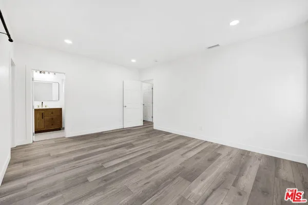 a view of an empty room with wooden floor and a fireplace