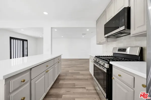 a kitchen with granite countertop cabinets stainless steel appliances and wooden floor