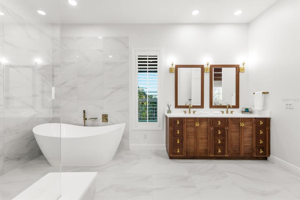 16895 1st Street East North Redington Beach, FL 33708 - Photo 49 of 97 a spacious bathroom with a tub a double vanity sink a mirror and a window