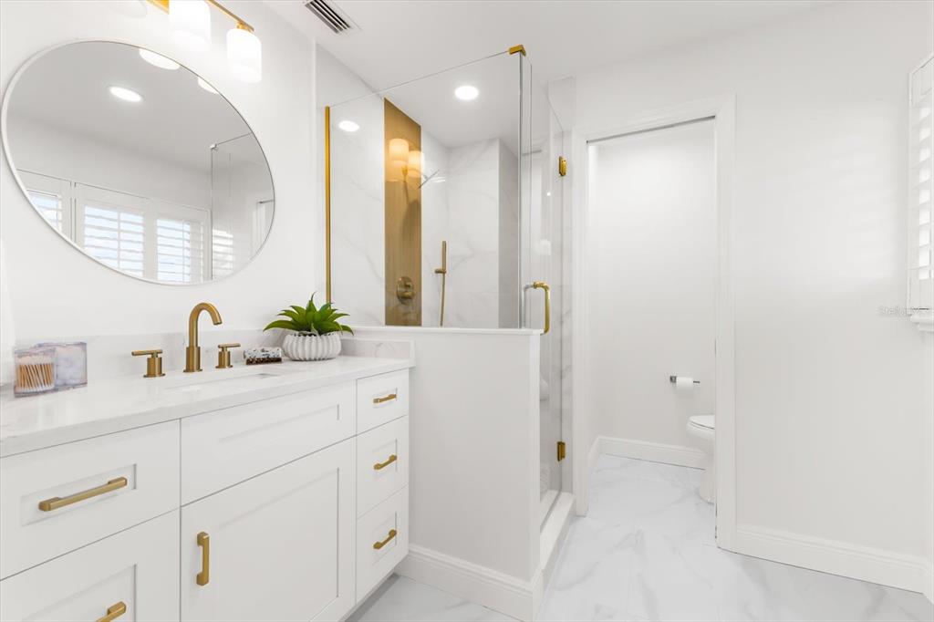 16895 1st Street East North Redington Beach, FL 33708 - Photo 55 of 97 a spacious bathroom with a granite countertop sink a toilet a mirror and vanity