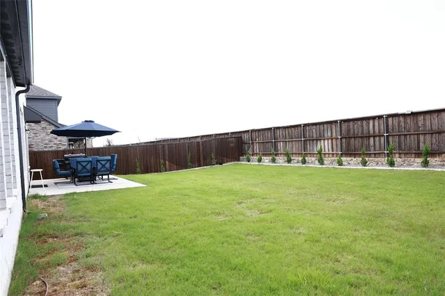 a view of a backyard with table and chairs a barbeque and wooden fence