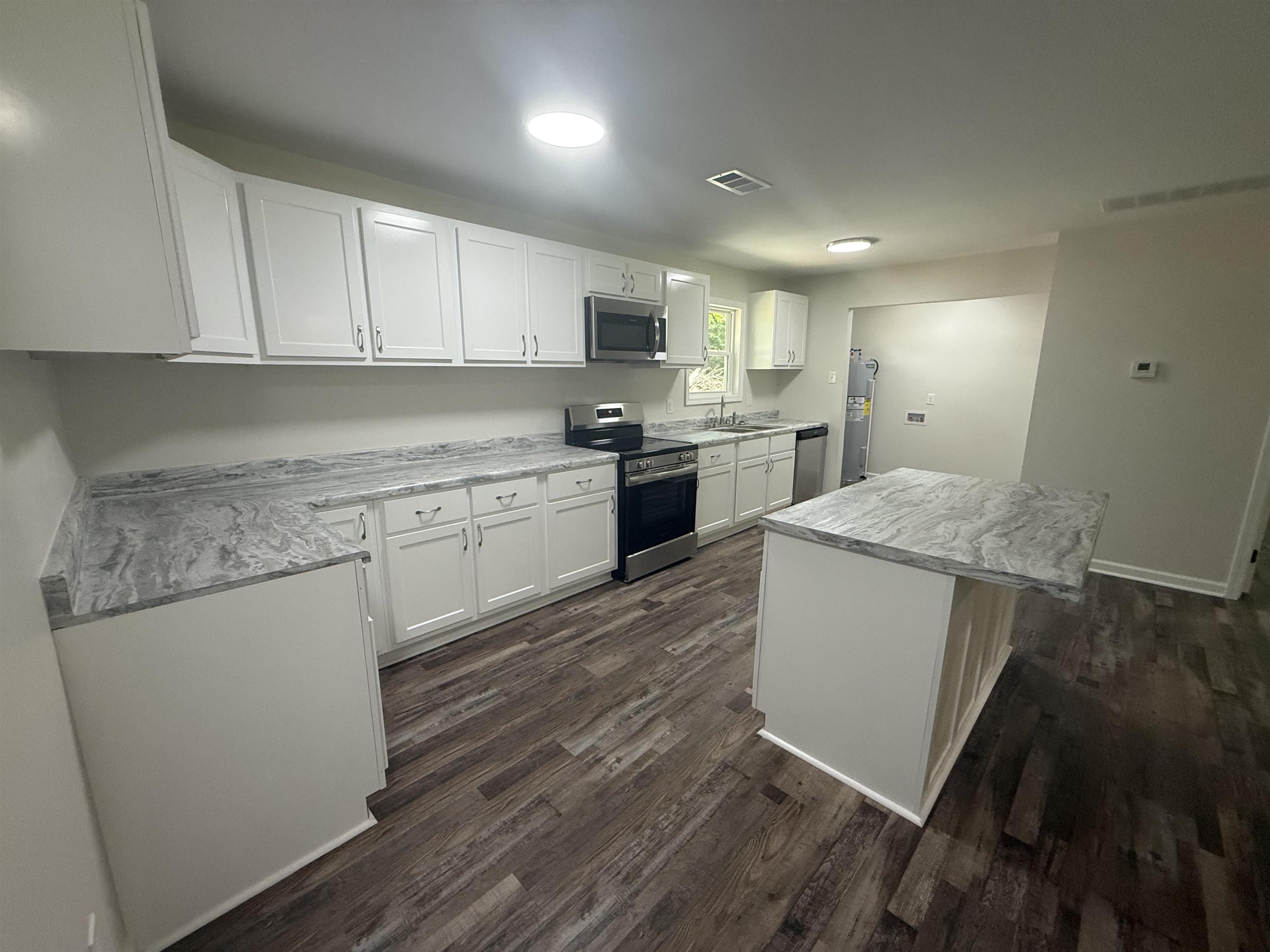 195 Poole Road Moscow, TN 38057 - Photo 8 of 21 Modern kitchen featuring white shaker cabinetry, wood-finish flooring, a central island with countertop seating, stainless steel appliances, and a double basin sink