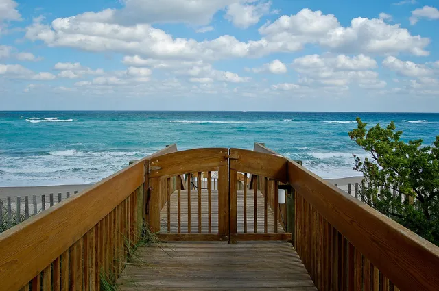 a view of a balcony with wooden floor and fence next to a yard