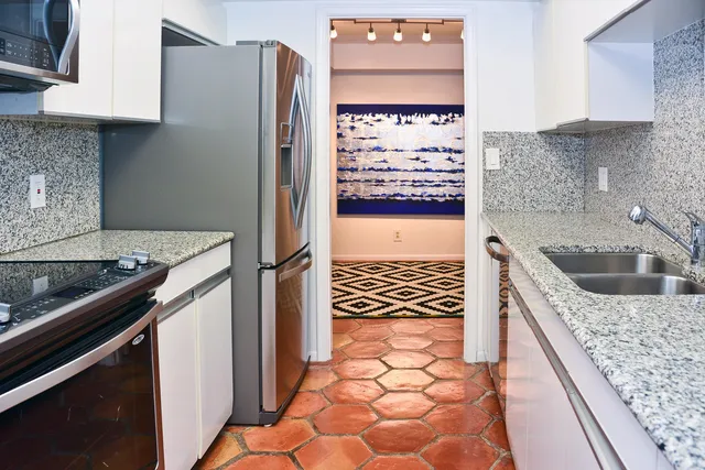 a kitchen with granite countertop a sink a stove and refrigerator