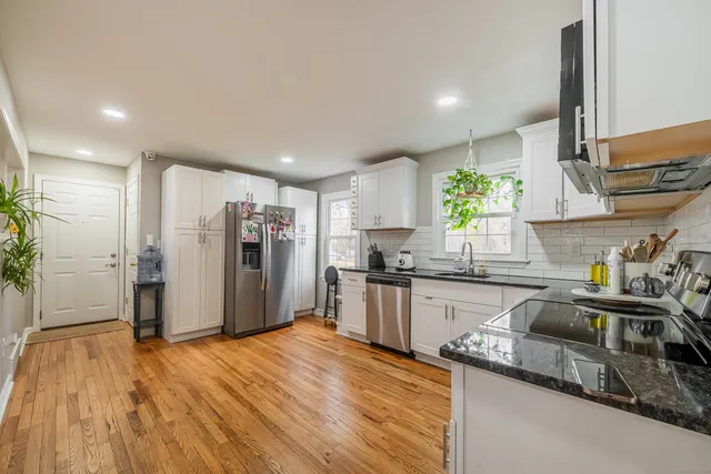 a kitchen with stainless steel appliances granite countertop a refrigerator a sink a stove and wooden floors