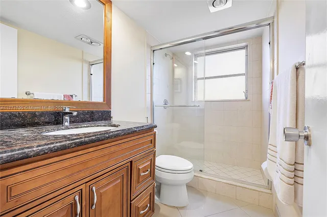 a bathroom with a granite countertop sink toilet and shower