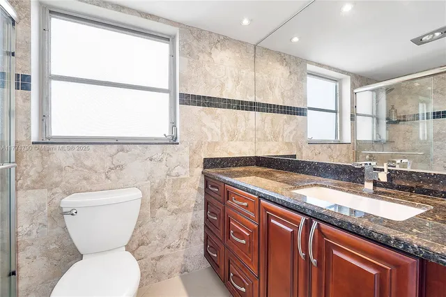 a bathroom with a granite countertop toilet sink and mirror