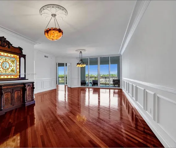 a view of an empty room with wooden floor and fan