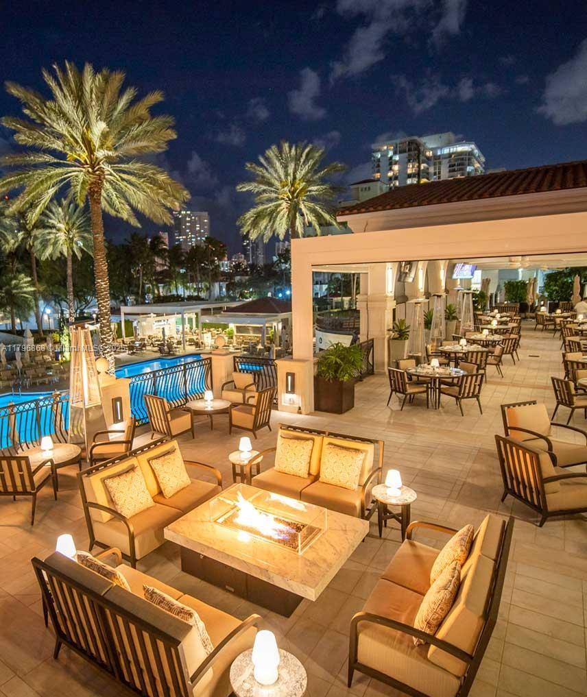 20165 Northeast 39th Place, Unit 403 Aventura, FL 33180 - Photo 34 of 40 a view of a patio with swimming pool table and chairs