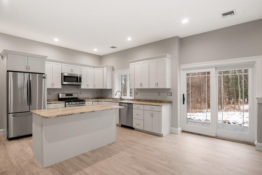 6 West Knoll Road Andover, MA 01810 - Photo 41 of 42 a large kitchen with stainless steel appliances granite countertop a stove a sink dishwasher a refrigerator and white cabinets with wooden floor