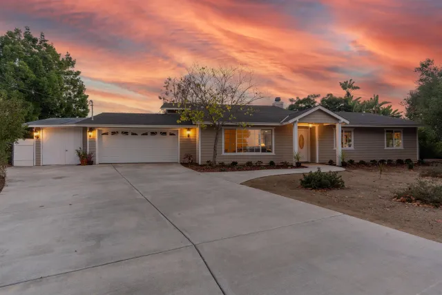 a front view of a house with yard and a tree