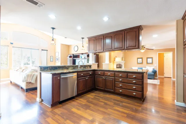 a kitchen with granite countertop a sink cabinets and wooden floor