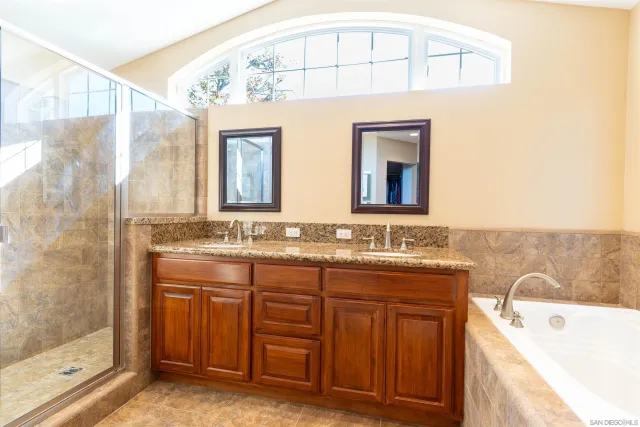a bathroom with a double vanity sink mirror and bathtub