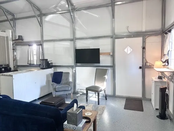 a living room with furniture a flat screen tv and a refrigerator
