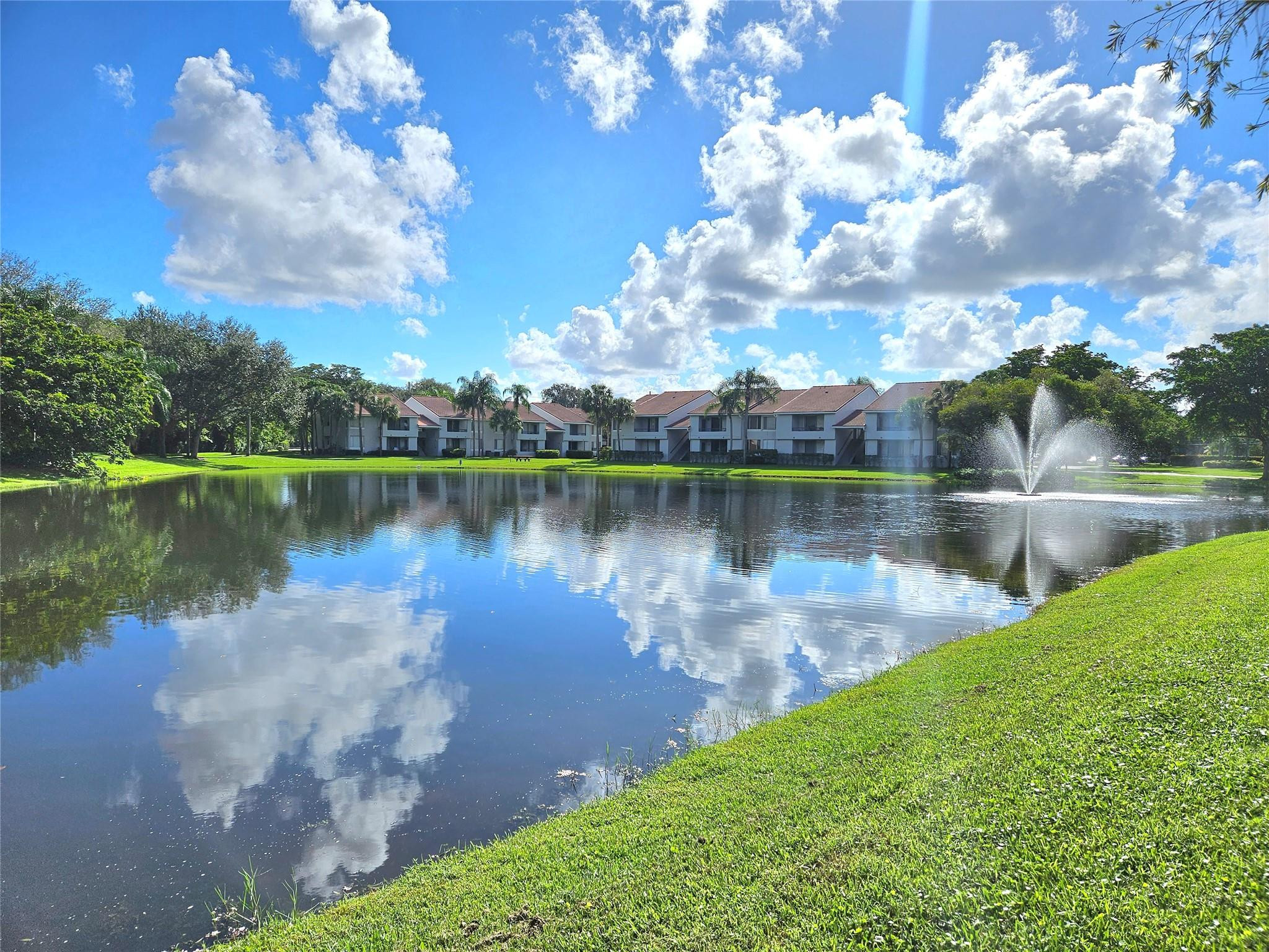 651 Lyons Road, Unit 10202 Coconut Creek, FL 33063 - Photo 14 of 28 a view of a lake with houses in the back