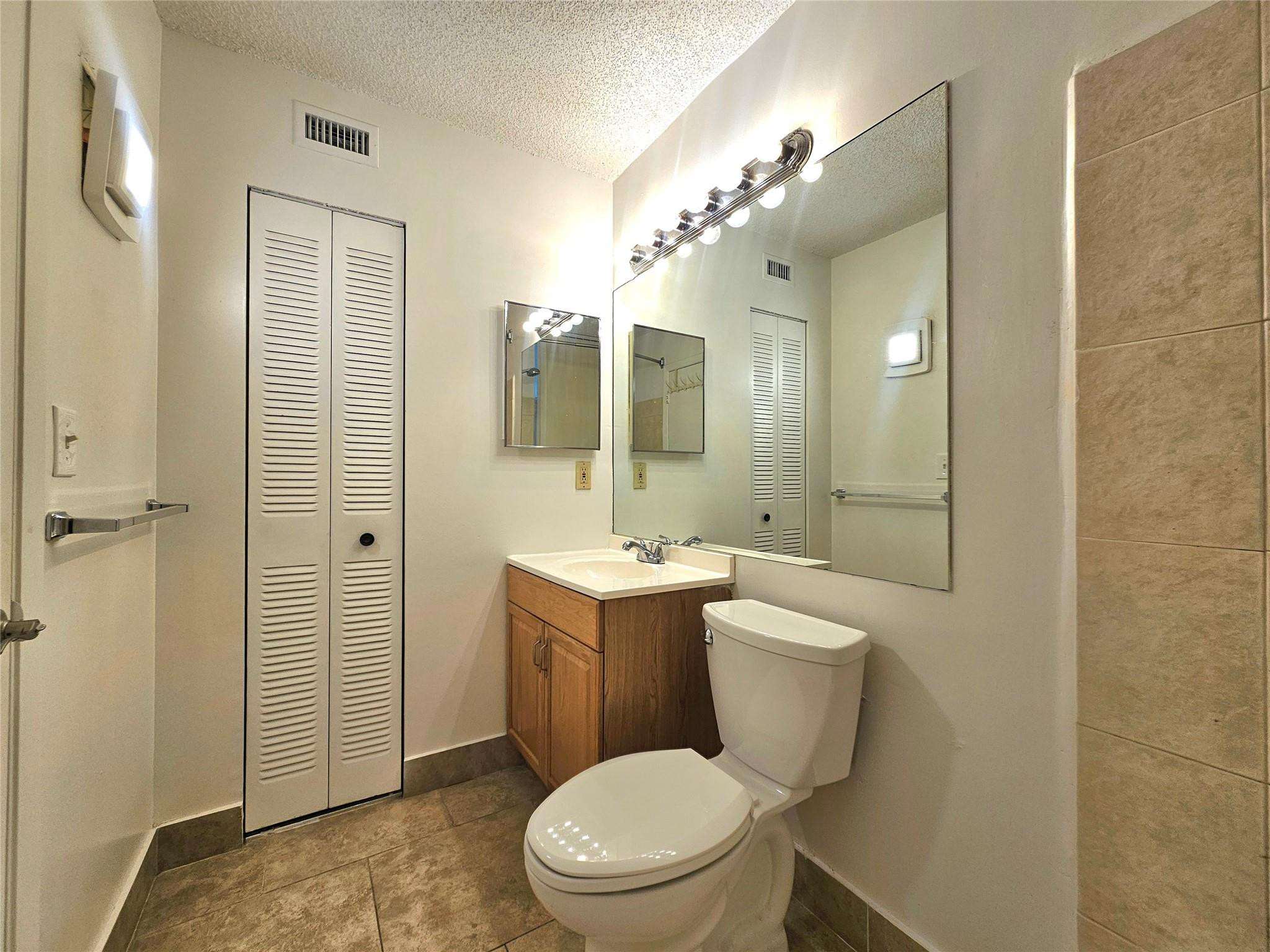651 Lyons Road, Unit 10202 Coconut Creek, FL 33063 - Photo 8 of 28 a bathroom with a toilet a sink and mirror