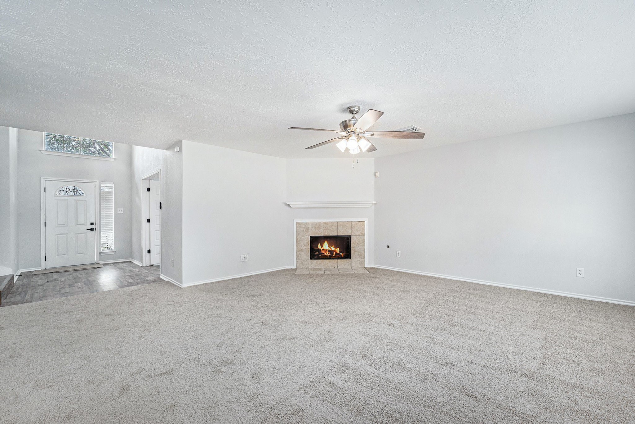 18131 Stone Trail Manor Drive Humble, TX 77346 - Photo 11 of 31 an empty room with a fireplace and chandelier fan