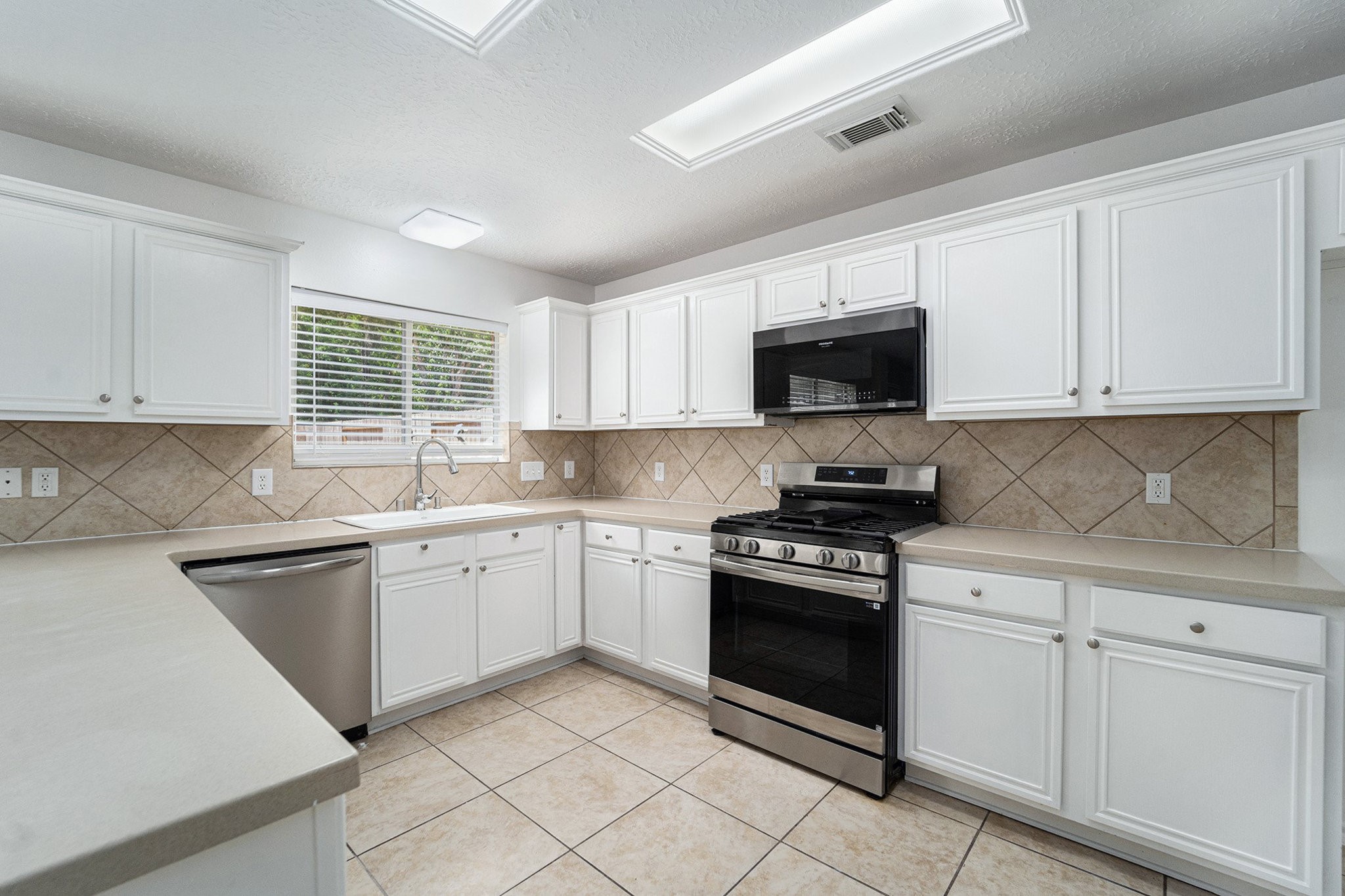 18131 Stone Trail Manor Drive Humble, TX 77346 - Photo 13 of 31 a kitchen with white cabinets and black appliances