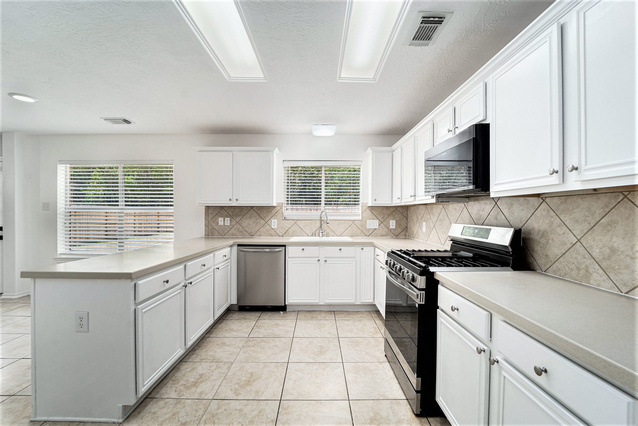 18131 Stone Trail Manor Drive Humble, TX 77346 - Photo 14 of 31 a kitchen with granite countertop white cabinets white appliances a sink and a window
