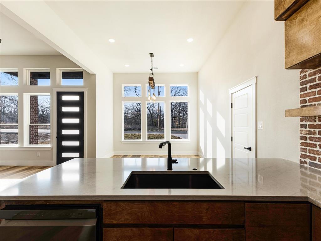 5018 Point La Vista Road Malakoff, TX 75148 - Photo 6 of 32 Kitchen with stainless steel dishwasher, light stone countertops, decorative light fixtures, and dark wood finish cabinets