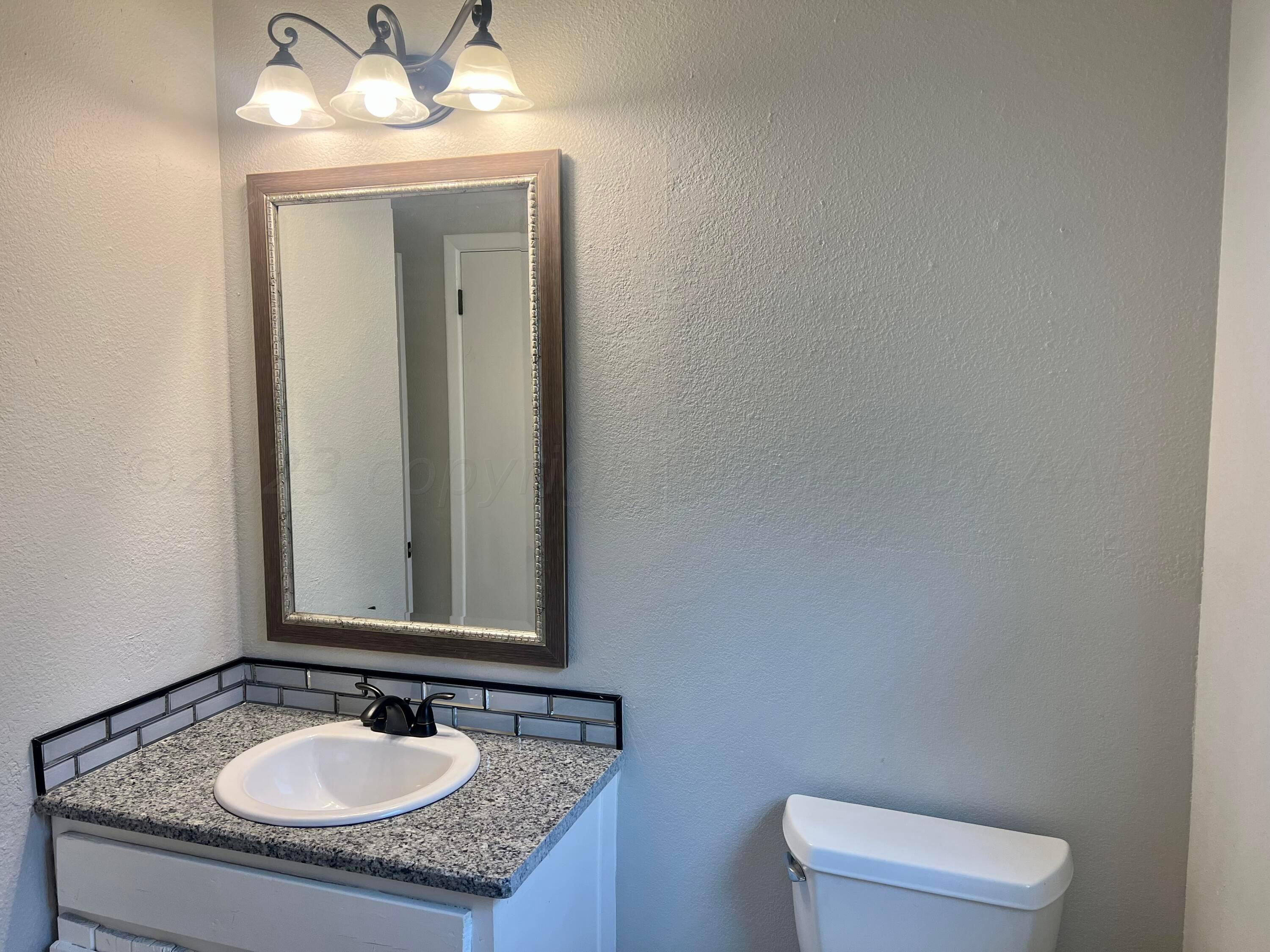 2903 Bagarry Street Amarillo, TX 79103 - Photo 19 of 26 a bathroom with a granite countertop sink a toilet and a mirror